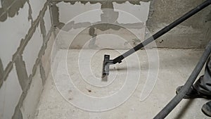 Worker washes the floor with a vacuum cleaner from industrial concrete dust and cement mud during home renovation. A