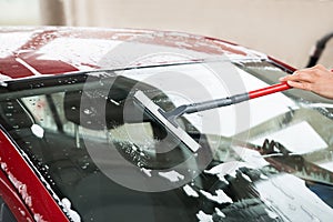 Worker Washing Windshield Of Car At Service Station