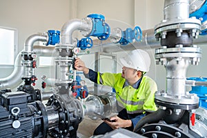 A worker at a water supply station inspects water pump valves equipment in a substation for the distribution of clean water at a