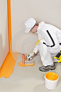 Worker waterproofing around the wall, floor and siphon