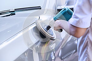 Worker waxing a car with auto polisher