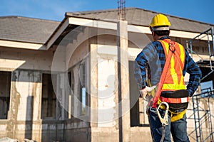 A worker wearing fall protection safety clothing  with hooks at construction site. Safety body construction, Working at height