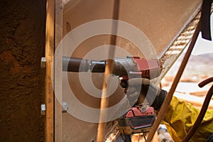 Worker wearing a glove using rattled gun tensioning nut attached onto the structure metal wal