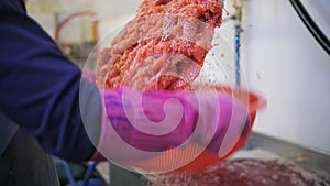 A worker wearing gloves pours red caviar salt and mixes it up. Slow motion