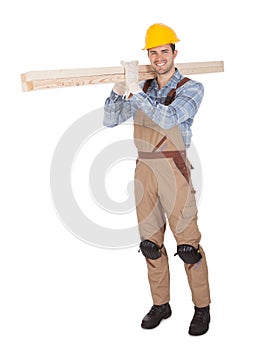 Worker wearing hard hat and carrying timber