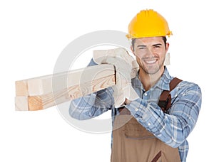 Worker wearing hard hat and carrying timber