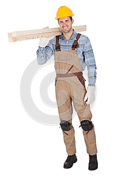 Worker wearing hard hat and carrying timber