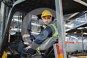 worker wearing helmet with driving forklift backwards in warehouse