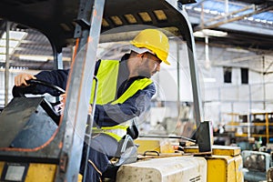 worker wearing helmet with driving forklift backwards in warehouse