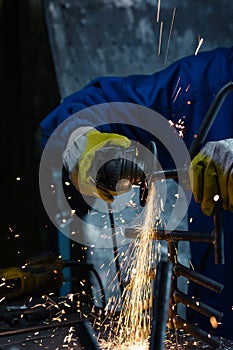 Worker wearing protection equipment using an angle grinder on metal