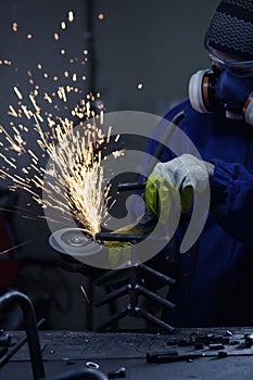 Worker wearing protection equipment using an angle grinder on metal and making sparks