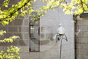 A worker wearing a protective gear cleaning a stone facade photo