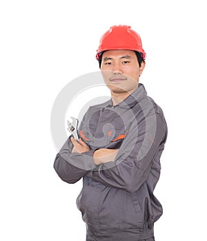 Worker wearing a red hard hat holding a wrench in hand standing in front of white background with his arms