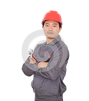 Worker wearing a red hard hat holding a wrench in hand standing in front of white background with his arms