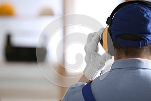 Worker wearing safety headphones indoors, back view with space for text. Hearing protection device