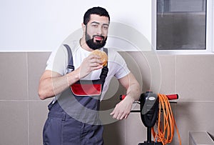 Worker wearing uniform eating burger during lunch break