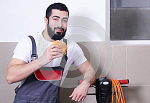 Worker wearing uniform eating burger during lunch break