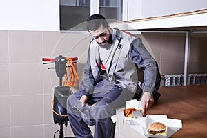 Worker wearing uniform eating burger during lunch break