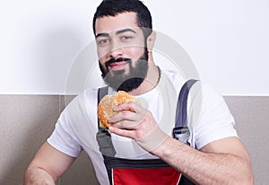 Worker wearing uniform eating burger during lunch break