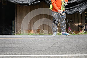 Worker wearing uniform is striping with measuring on the road