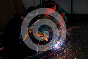 Worker weld metal with a arc welding machine at industrial facility.