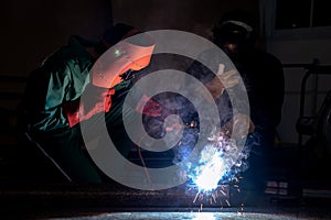 Worker weld metal with a arc welding machine at industrial facility.