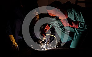 Worker weld metal with a arc welding machine at industrial facility.