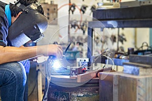 Worker or welder wearing a mask for protect light and smoke during welding metal part or workpiece at factory and sparkle bright