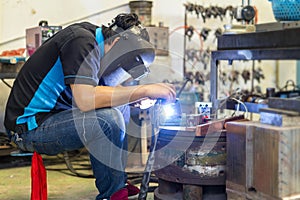 Worker or welder wearing a mask for protect light and smoke during welding metal part or workpiece at factory and sparkle bright