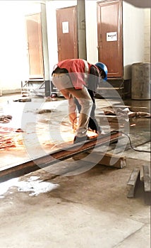 A worker in welding a iron sheet on a project.