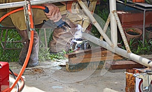 Worker with a welding machine fixing a caster wheels, fiery sparks flying around