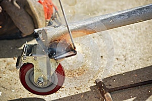 Worker with a welding machine fixing a caster wheels, fiery sparks flying around