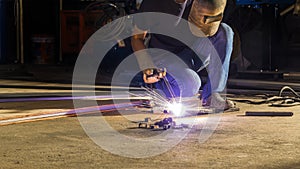 worker welding metal, focus on flash light line of sharp spark,in low light