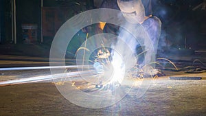 worker welding metal, focus on flash light line of sharp spark,in low light