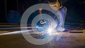 worker welding metal, focus on flash light line of sharp spark,in low light