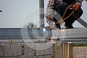 The worker welding metal on roof structure