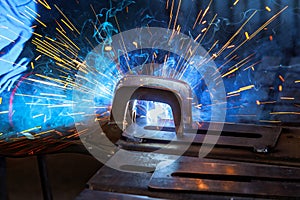 A worker welding steel with gas argon creates sparks that can cause smoke in workplace