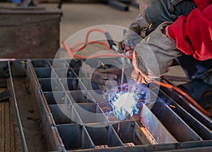 Worker welding steel grill pipe cap in factory