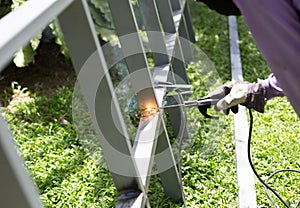 Worker welding a Steel Iron Bar for a New Fence Frame