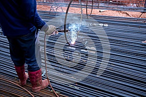 Worker welding steel rebar for reinforcement concrete in the construction site