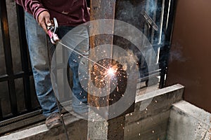 Worker welding steel with spark lighting and smoke at constructi