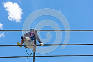 Worker welding the steel structure of roof with arc welding machine and blue sky in background
