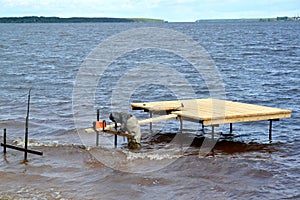 The worker welds metal designs of a pier in the Rybinsk reservoir. Yaroslavl region