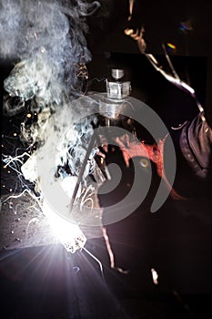 Worker welds metal structures by electric arc welding
