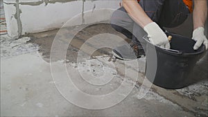 A worker wets a concrete floor with a brush for further waterproofing. Primer of a concrete floor before laying tiles on it, the