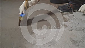 Worker wets the concrete floor with a brush. Primer concrete floor for waterproofing