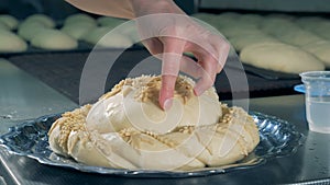 A worker wets pie decorations for a pie before adding them.