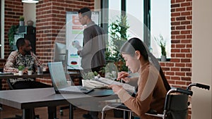 Worker in wheelchair analyzing business charts on documents