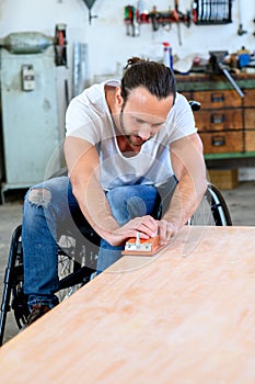 Worker in wheelchair in a carpenter`s workshop