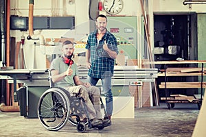 Worker in wheelchair in a carpenter`s workshop with his colleagu